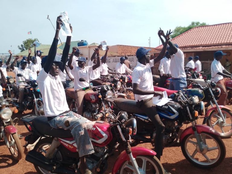 Riders raise campaign materials at the launch in Kuajok