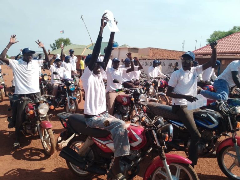 Riders raise campaign materials during the ride